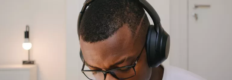 Person wearing headphones and glasses, concentrating.