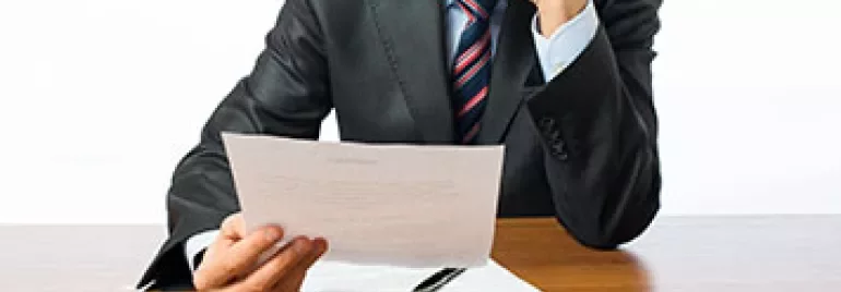 A person reading a document at a wooden table.