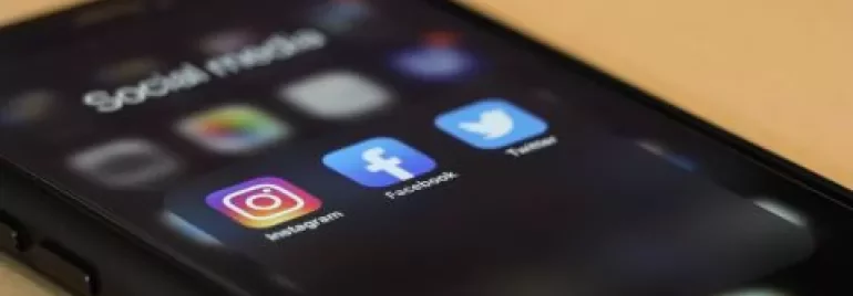 Smartphone displaying Instagram, Facebook, and Twitter icons on screen.