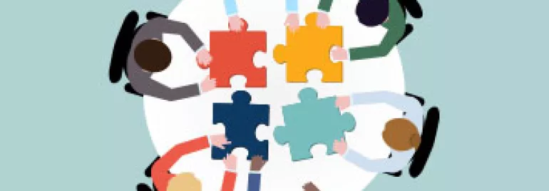 Group of people collaborating on puzzle pieces at a table.