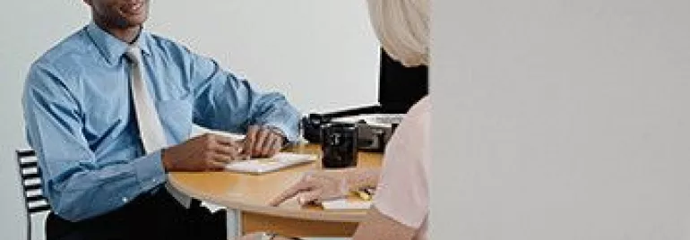 Two people having a discussion at an office table.