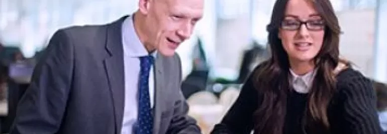 Two people collaborating at a computer in an office setting.