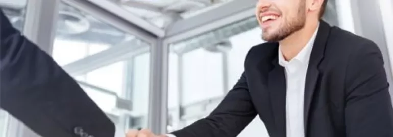 Person in suit shaking another person's hand in an office.