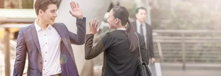 Two people high-fiving in a business setting.