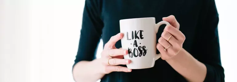 Persoon houdt een mok vast met de tekst 'Like a Boss'.