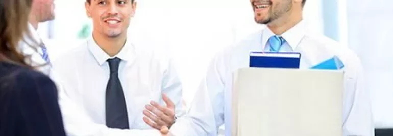 People shaking hands in an office setting, smiling.