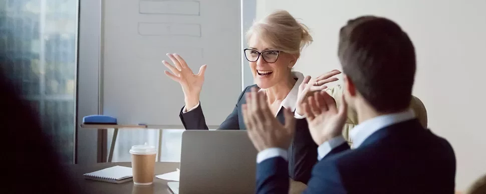 Two people clapping in a meeting room.