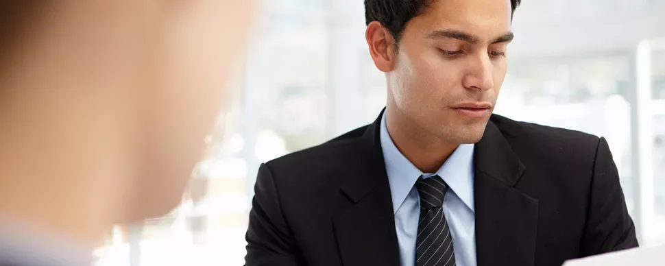 A person in a business suit reviewing papers.