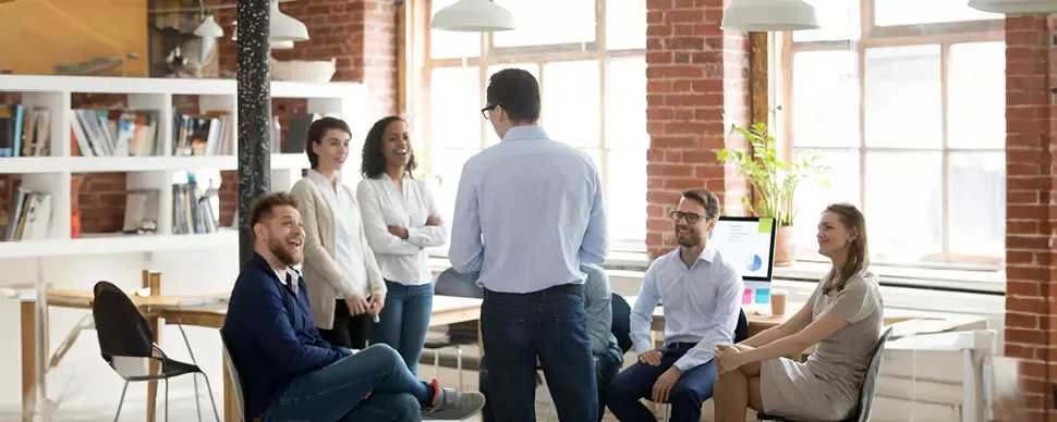 A group of people having a casual meeting in a brick-walled office.
