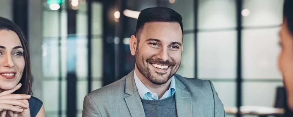 Drie mensen in een gesprek in een moderne kantoorruimte.