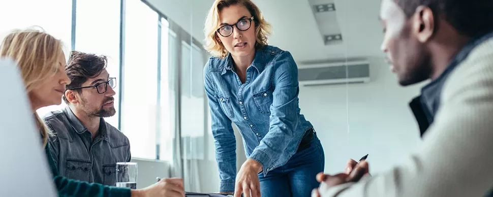 Professional woman presenting to her colleagues in a modern office setting.