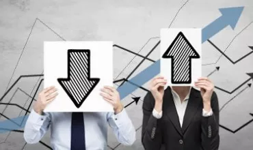 Two people holding arrow signs next to financial graphs.