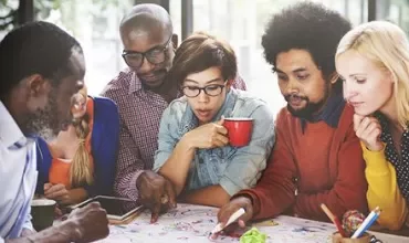 A group of people working together at a table with notes and pens.
