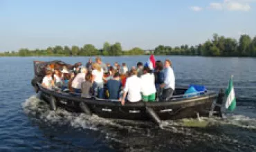 Groep mensen geniet van een boottocht op een zonnig meer.