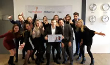 Group of people cheerfully posing with a sign.