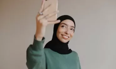 Persoon maakt een selfie met een smartphone, glimlachend.
