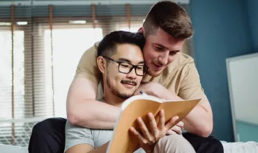 Twee mensen lezen samen een boek op de bank.