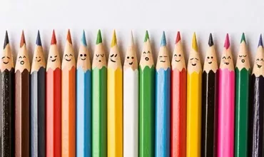 Color pencils with drawn faces, arranged in a row.