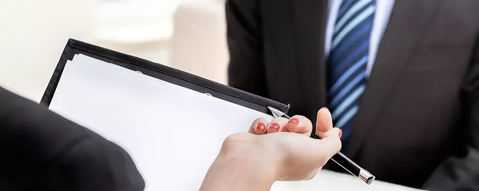 Hand holding a pen and document in a business meeting.