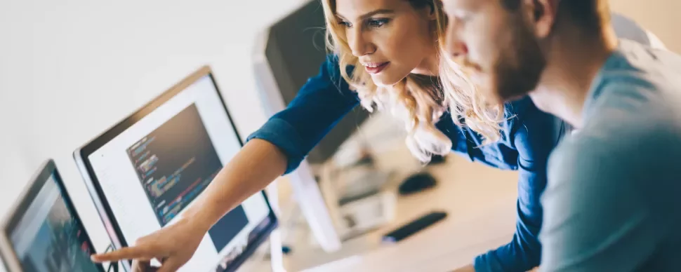 Collega's werken samen op een computer, wijzend naar het scherm.