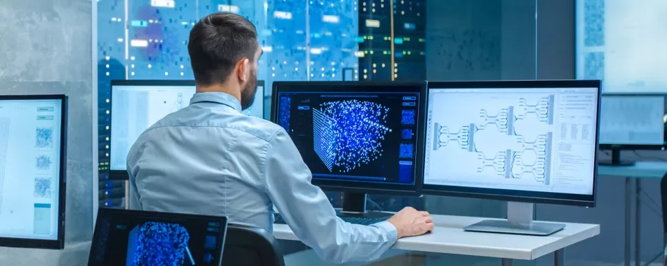 Persoon werkt op computerschermen met data en diagrammen.