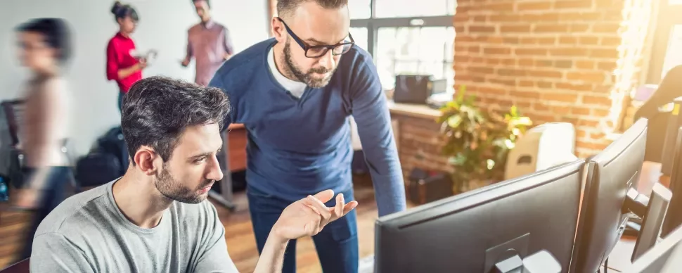 Twee mensen werken samen aan een computer in een modern kantoor.