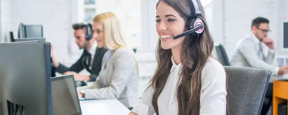 Klantenservicemedewerkers werken aan bureaus met headsets.