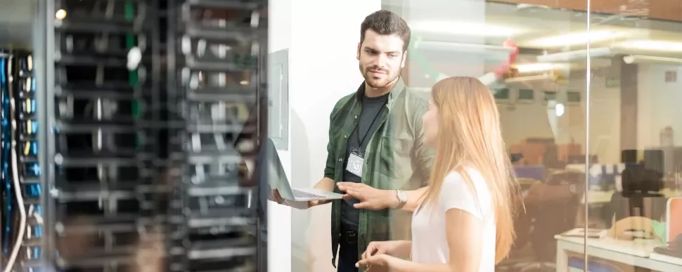 Mensen discussiëren en gebruiken een laptop in een serverruimte.