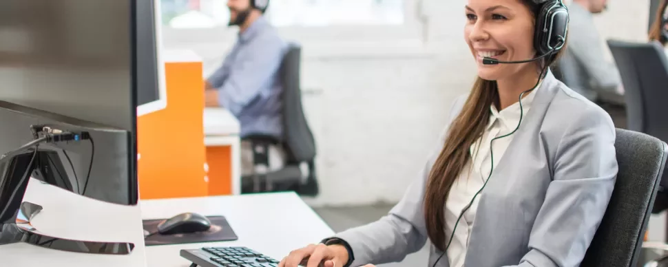 Persoon met headset werkt aan een computer in een kantoor.