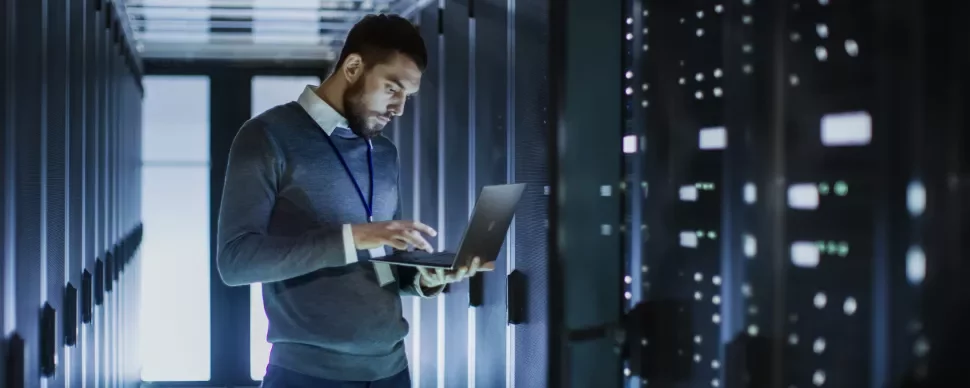 Persoon werkt op laptop in serverruimte