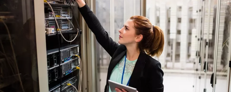 Persoon werkt in een serverruimte, bezig met kabels en apparatuur.