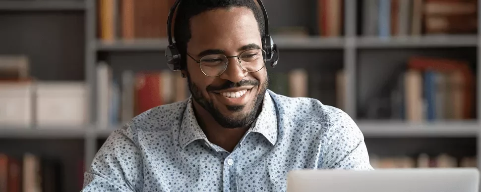 Persoon met een headset voor laptop, omringd door boeken in een kast.