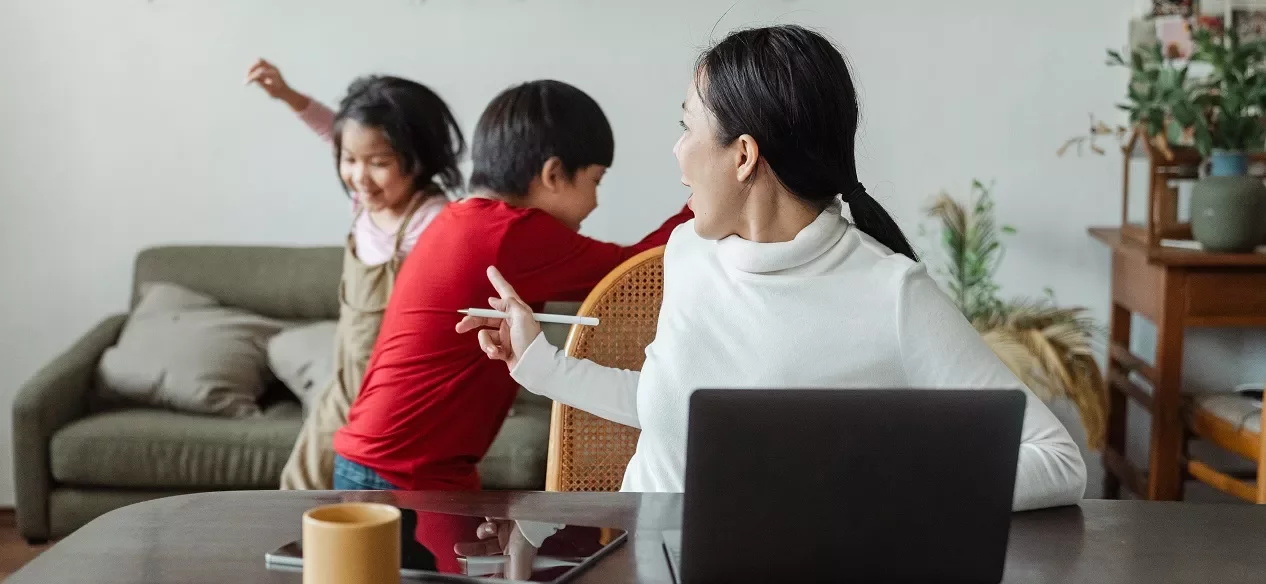 Vrouw kijkt naar kinderen die in de woonkamer spelen.