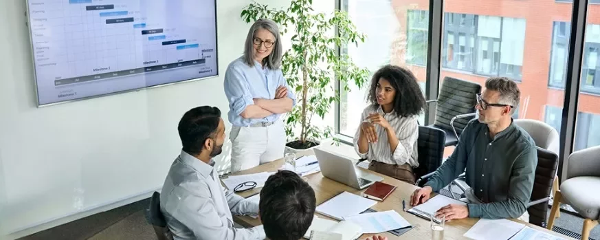 Groep collega’s in een vergaderruimte met een presentatie op het scherm.