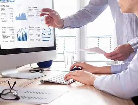 People reviewing financial charts and graphs on a computer screen.