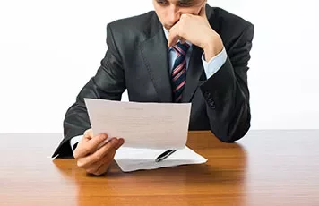 Een persoon leest een document aan een houten tafel.