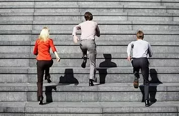 Three people running up a stone staircase.