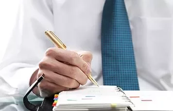 Hand met pen schrijft in een agenda