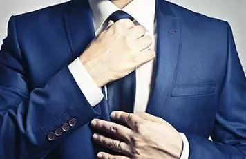 Person adjusting a tie on a blue suit.