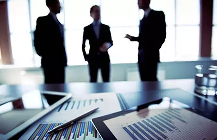 Group discussing in an office with charts on a table.