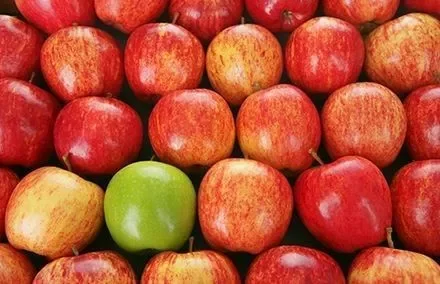 A row of red apples with one green apple in the center.