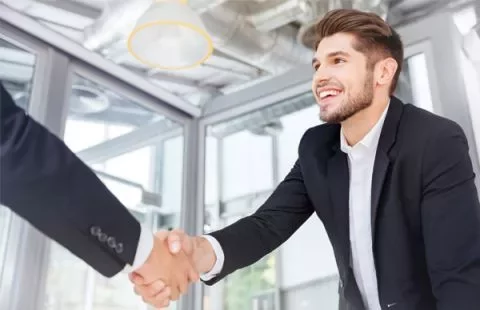 Person in suit shaking another person's hand in an office.