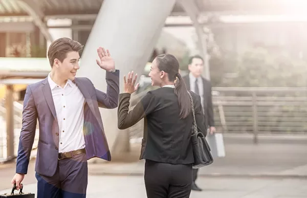 Two people high-fiving in a business setting.